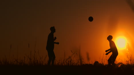 Zwei-Jungen-Spielen-Bei-Sonnenuntergang-Fußball.-Silhouette-Von-Kindern,-Die-Bei-Sonnenuntergang-Mit-Einem-Ball-Spielen.-Das-Konzept-Einer-Glücklichen-Familie.